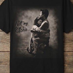 May include: Black t-shirt featuring a sepia-toned image of a couple embracing, with the text "Not my Ritchie...". The image shows a man and woman in a tender moment. The shirt is made of a soft material.