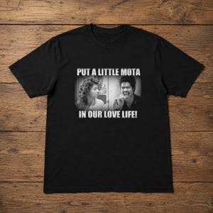 May include: Black t-shirt with a black and white image of two people and the text "PUT A LITTLE MOTA IN OUR LOVE LIFE!". The t-shirt is made of a soft material and has a crew neck.