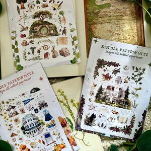 Peut inclure: Plusieurs inserts Kindle Paperwhite avec des illustrations. L'un d'eux pr&eacute;sente une carte, tandis que d'autres pr&eacute;sentent des autocollants th&eacute;matiques avec des images d'un trou de hobbit, d'une maison et d'autres &eacute;l&eacute;ments d&eacute;coratifs. Le texte "KINDLE PAPERWHITE" est visible.