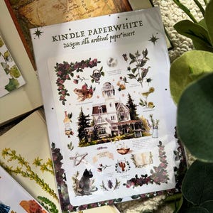 Peut inclure: Une insertion Kindle Paperwhite avec une illustration fantaisiste repr&eacute;sentant une maison victorienne, un chat noir et des &eacute;l&eacute;ments botaniques. L'insert est entour&eacute; d'une bordure de roses rouge fonc&eacute; et contient le texte "Kindle Paperwhite 265gsm silk archival paper insert."