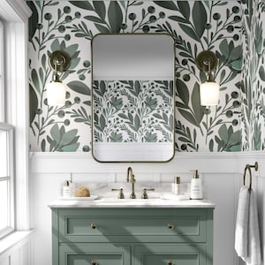 Peut inclure: Meuble de salle de bain vert sauge avec un comptoir en marbre et un miroir rectangulaire. Les murs sont décorés d'un papier peint floral vert et blanc. Deux appliques avec des abat-jours en verre blanc encadrent le miroir.