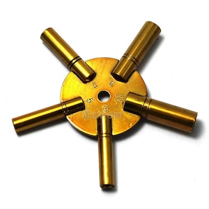 May include: A brass watch key winding tool with five different sized keys. The keys are numbered 3, 5, 7, 9, and 11.