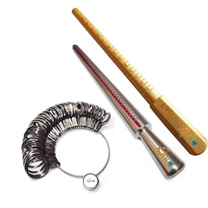May include: A set of three ring sizers for measuring finger size. The set includes a wooden ring sizer, a metal ring sizer, and a set of metal ring sizers on a chain. The ring sizers are marked with numbers indicating ring sizes.
