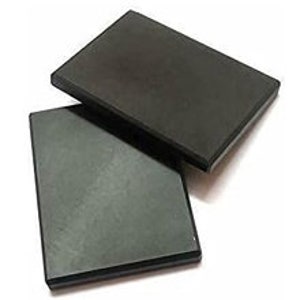 May include: Two rectangular, black soapstone coasters are stacked on a white background. The coasters have a smooth, matte finish and a slightly beveled edge. They appear to be new and unused.