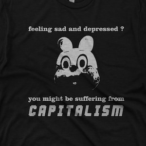 Puede incluir: Camiseta negra con un conejo de dibujos animados blanco y el texto "feeling sad and depressed? you might be suffering from CAPITALISM".