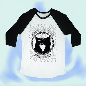 May include: A white and black baseball tee shirt with a black and white graphic of a cat's head in a circle with the text "Amyl & The Sniffers" around the circle.