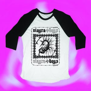 May include: A white and black baseball tee shirt with a black and white graphic of a scorpion with the text "viagra boys" on it.