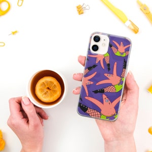 May include: Purple iPhone 13 phone case featuring a repeating pattern of Patrick Star from SpongeBob SquarePants wearing fishnet stockings and heels.  The case is clear and shows the phone's camera lenses. The design is vibrant and playful.