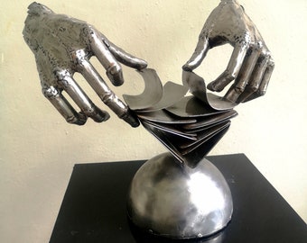 Poker game.Modern tabletop sculpture of a croupier's hands shuffling a deck of cards, made of metal by electric welding