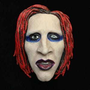 Die Sammelfigur von Marilyn Manson wird aus Polyurethanharz gefertigt, mit Acrylfarben bemalt und lackiert. Souvenir mit Magnet.
