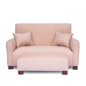 May include: A light pink loveseat sofa featuring rounded armrests and a matching rectangular ottoman. The sofa includes two square throw pillows in the same light pink fabric, and both pieces are supported by dark brown wooden block feet.