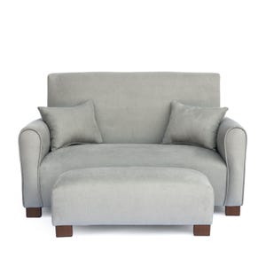 May include: A light gray loveseat with rounded arms and a matching rectangular ottoman. The loveseat features a high backrest, two square throw pillows in the same light gray fabric, and four short, dark brown wooden legs on both pieces.