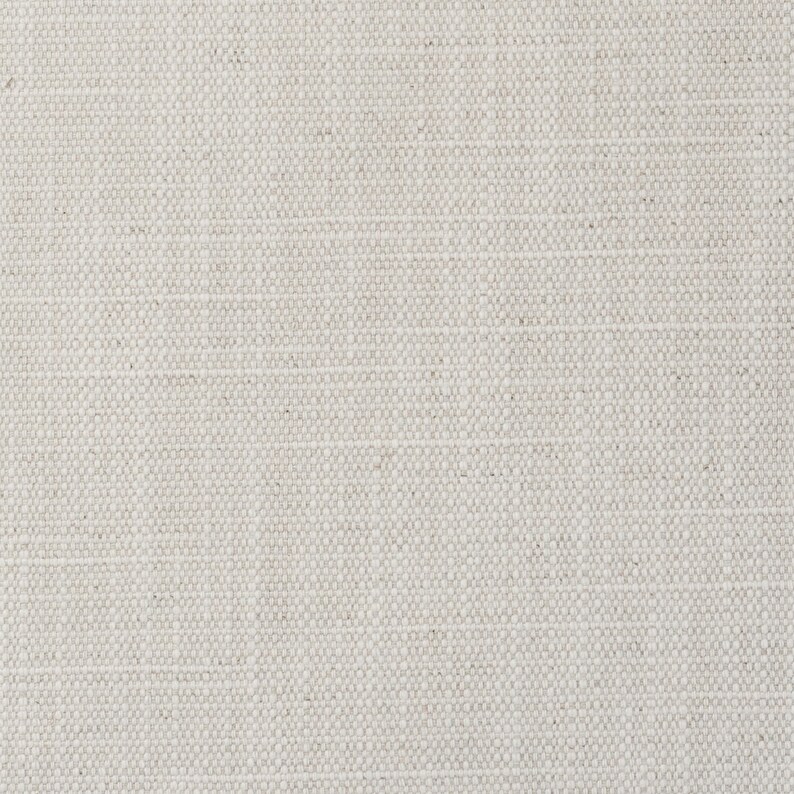 May include: A close-up view of a light beige fabric with a visible woven texture. The material features a consistent grid-like pattern created by the interlacing of horizontal and vertical threads, resulting in a neutral, off-white appearance.