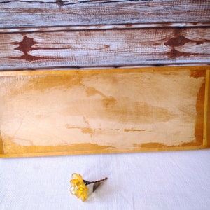 May include: A rectangular wooden serving tray with a light brown finish. The tray has a slightly rounded edge and a smooth surface.
