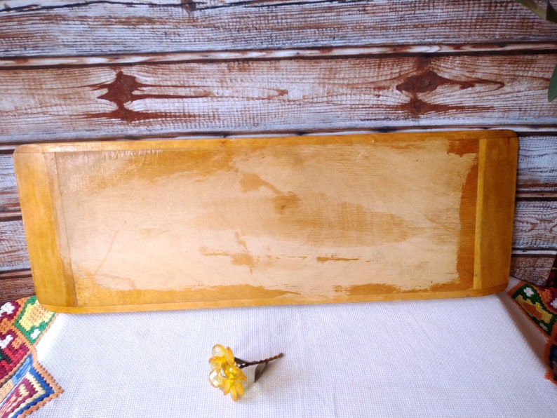 May include: A rectangular wooden serving tray with a light brown finish. The tray has a slightly rounded edge and a smooth surface.