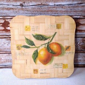 Puede incluir: Una bandeja de servir cuadrada de bambú tejido con un diseño pintado de una rama de limón con dos limones. La bandeja tiene las palabras "Lemon", "Basket", "A bright green leaf", "Juicy and tasty pulp" y "Welcome you while enjoying tasty homemade lemonade or a smoothie with lemon" impresas en ella.