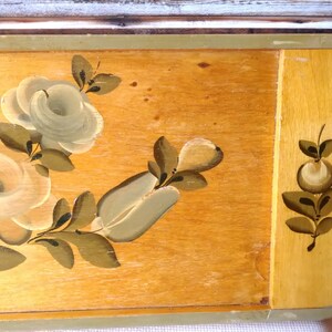 May include: A wooden tray with a painted floral design. The tray features white and green roses and leaves on a light brown background. The edges of the tray are painted a light green color.
