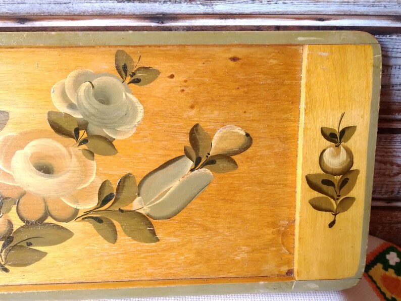 May include: A wooden tray with a painted floral design. The tray features white and green roses and leaves on a light brown background. The edges of the tray are painted a light green color.