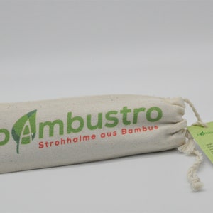 May include: A white canvas bag with a drawstring closure. The bag has a green logo that says "bambustro" and the text "Strohhalme aus Bambus". The bag is sitting on a white surface.