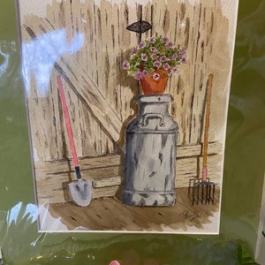 May include: A watercolor painting depicting a rustic scene with a tall, weathered metal milk can topped by a terracotta pot filled with small pink flowers. A shovel with a pink handle and a garden fork with a wooden handle lean against a wooden wall.
