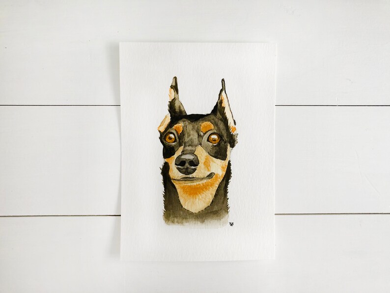 May include: Watercolor painting of a black and tan dog with brown eyes. The dog is looking directly at the viewer with a slight smile.