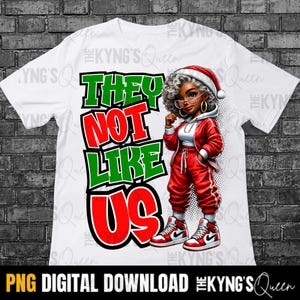 May include: White t-shirt with a red, green, and white graphic that says "They Not Like Us". A cartoon woman with a Santa hat is wearing a red and white outfit and standing next to the text.