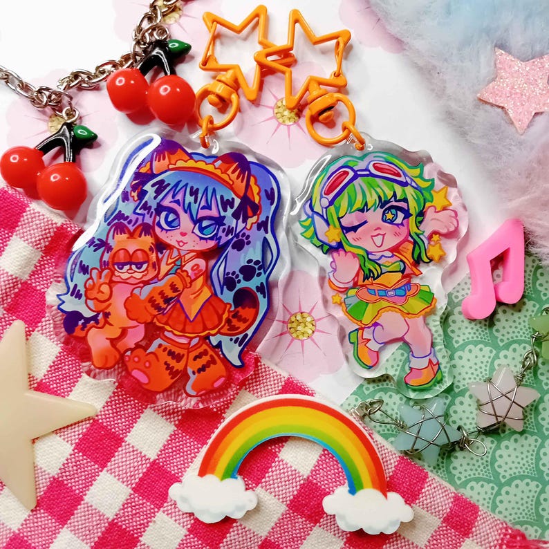 May include: Two colorful anime-style character charms with a rainbow, stars, and cherries. The charms are attached to a keychain with a star-shaped connector.
