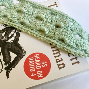 Może przedstawiać: Jasnozielona zakładka do książki wykonana na szydełku z kwadratowym wzorem. Zakładka leży na książce zatytułowanej "The Liar" autorstwa Stephena Fry'a. Okładka książki przedstawia czarno-białą ilustrację mężczyzny z ogonem.