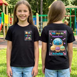 Puede incluir: Dos camisetas negras con diseños a juego. La parte delantera de la camiseta tiene la palabra "Name" encima de dibujos animados de albóndigas. La parte trasera de la camiseta tiene el texto "You Are An Awesome Dumpling" con un gráfico de albóndigas.