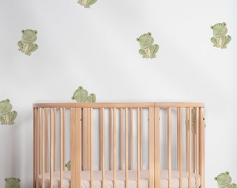 May include: A wooden oval crib with a white background featuring a pattern of green frog illustrations.