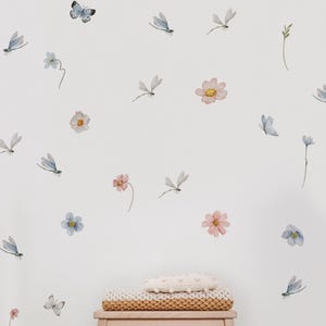 May include: A white wall with a variety of watercolor decals, including butterflies, dragonflies, and flowers. The decals are in shades of blue, pink, and yellow.