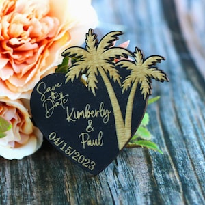 Puede incluir: Imán de madera negro en forma de corazón para guardar la fecha con palmeras doradas y el texto "Save the Date Kimberly & Paul 04/15/2023".