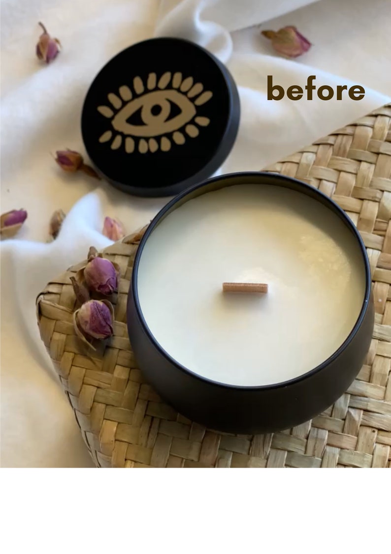 May include: A black candle with a white wax top and a wooden wick. The candle is in a black tin container with a lid that has a gold eye design. The word "before" is written on a white surface behind the candle.