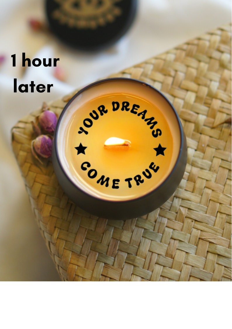 May include: A black candle with a yellow wax top and a white flame. The candle has the text "YOUR DREAMS COME TRUE" printed on the side.