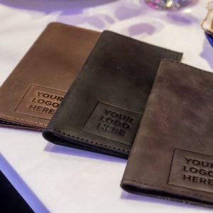 May include: Three leather-bound menu covers in brown, black, and dark brown. Each cover has a square embossed with the text "YOUR LOGO HERE".