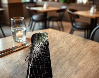 May include: A black alligator-embossed leather wallet with a black string closure.