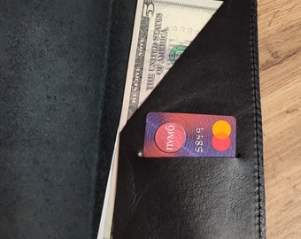 May include: Black leather wallet with a bill and a credit card visible. The wallet has a pocket for the credit card and a larger pocket for the bill. The credit card has the number 5849 on it.