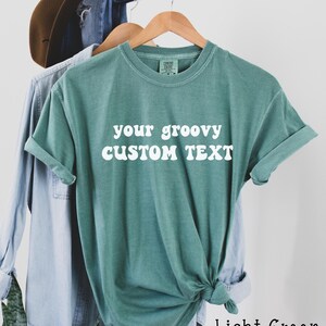 May include: Light green t-shirt with the text "your groovy CUSTOM TEXT" in white.
