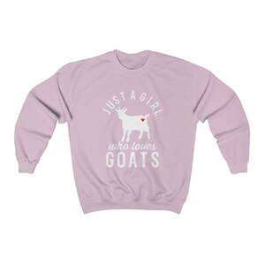 May include: A light pink sweatshirt with a white silhouette of a goat with a red heart on its side. The text "Just a girl who loves goats" is printed on the sweatshirt.