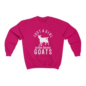 May include: A pink sweatshirt with the text "Just a girl who loves goats" in white. A white silhouette of a goat with a red heart is in the center of the text.