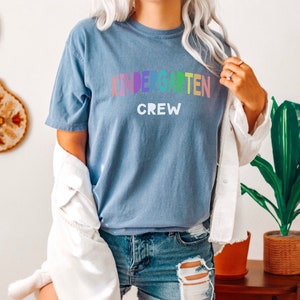 May include: A blue t-shirt with the text "Kindergarten Crew" in rainbow colors.
