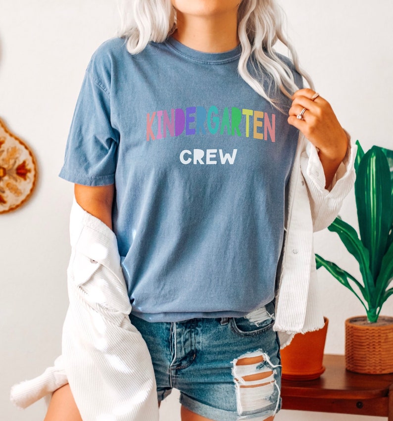 May include: A blue t-shirt with the text "Kindergarten Crew" in rainbow colors.