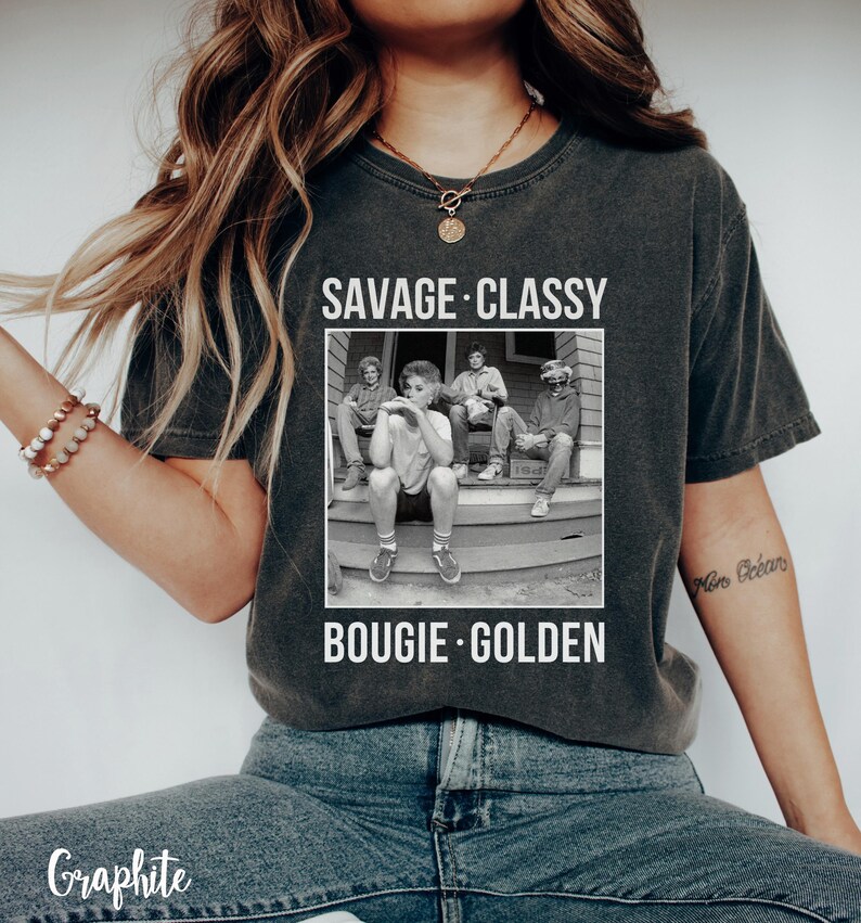 Puede incluir: Una camiseta gris oscuro con una foto en blanco y negro de cuatro personas sentadas en un porche. El texto "SAVAGE &middot; CLASSY &middot;  BOOGIE &middot; GOLDEN" est&aacute; impreso en la camiseta.