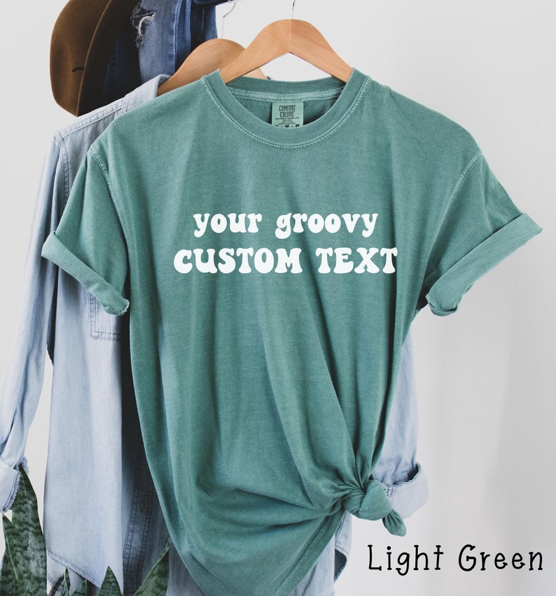 May include: Light green t-shirt with the text "your groovy CUSTOM TEXT" in white.