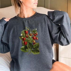 May include: A dark gray sweatshirt with a vintage illustration of a strawberry plant with red strawberries and green leaves.