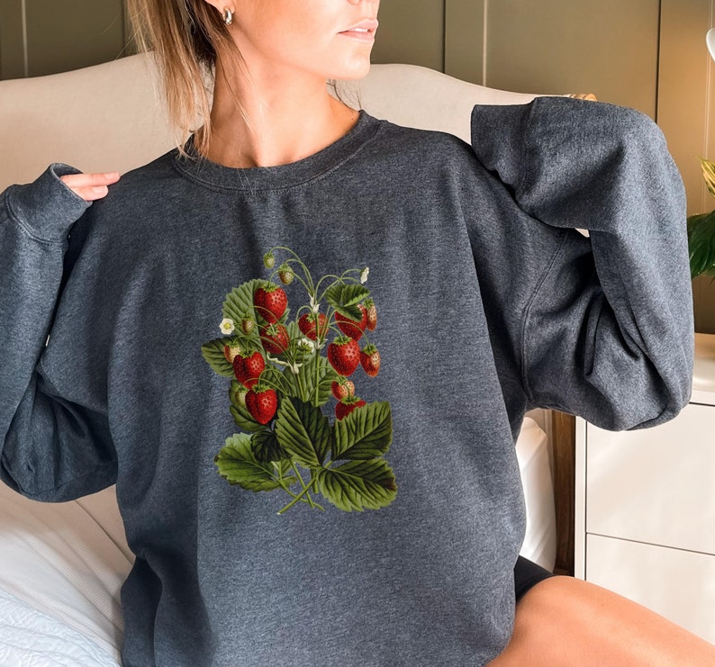 May include: A dark gray sweatshirt with a vintage illustration of a strawberry plant with red strawberries and green leaves.