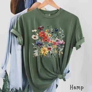 May include: A green t-shirt with a colorful floral print. The shirt is made of hemp.