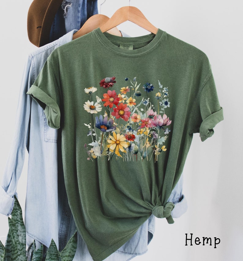 May include: A green t-shirt with a colorful floral print. The shirt is made of hemp.