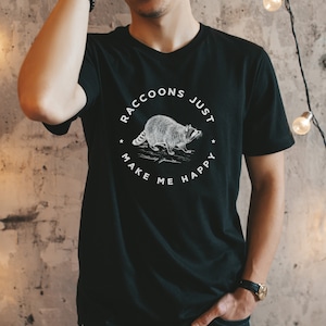 K&ouml;nnte beinhalten: Schwarzes T-Shirt mit einem wei&szlig;en Grafikdruck eines Waschb&auml;ren und dem Text "Raccoons Just Make Me Happy".