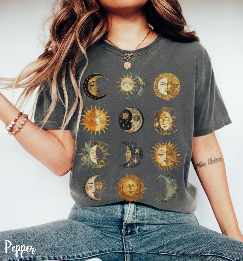 May include: A dark gray t-shirt with a vintage-style print of 12 moons and suns with faces. The print is in shades of gold, yellow, and blue.
